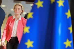 Ursula von der Leyen, President of the EU Commission, walks out from behind the EU flag