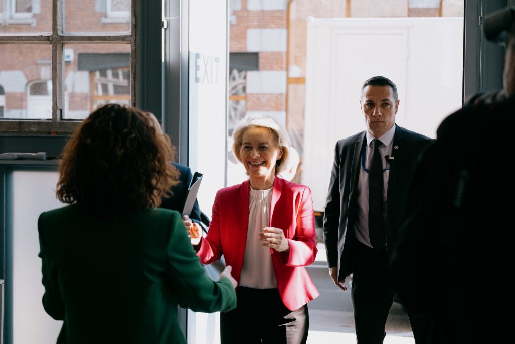 Ursula von der Leyen arrives at the European Employment and Social Rights Forum 2026 walking through a door and holding her hands out to greet someone. She wears a white shirt and pink jacket